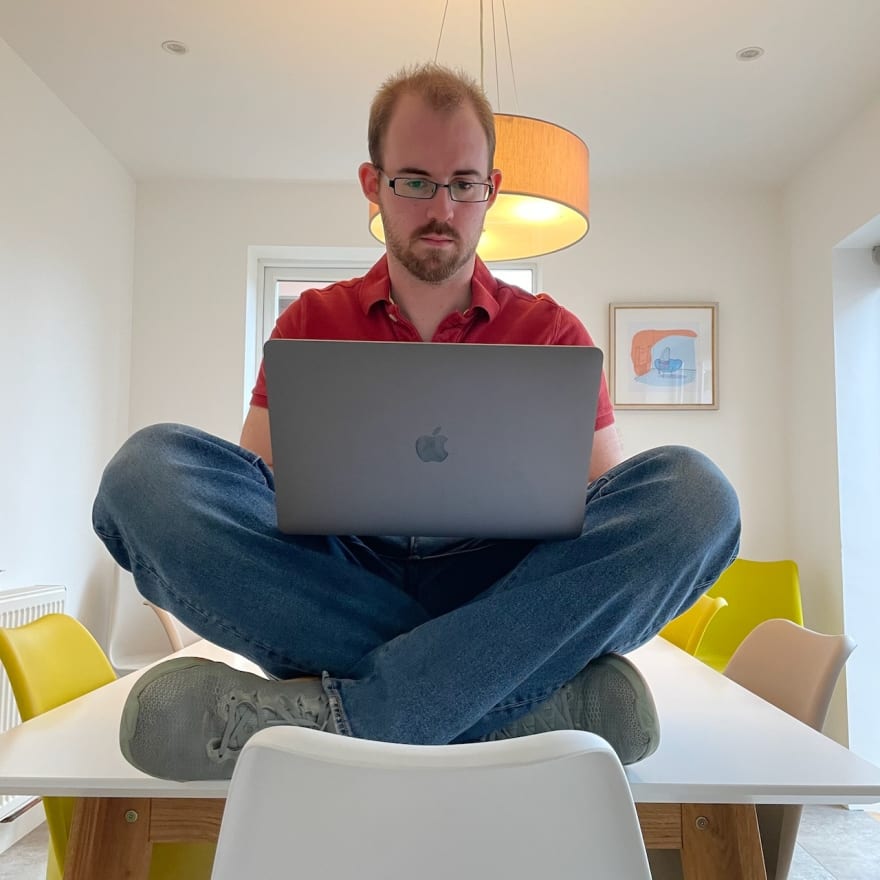 Person sat on table cross legged with a laptop