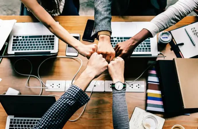 Fist bump of a team between all their laptops