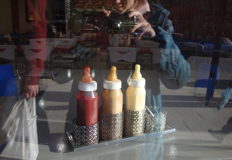 Three baby bottles filled with condiments