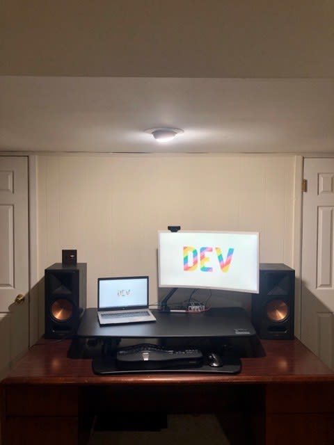 A massive computer riser with an arm mounted monitor and a pair of Klipsch RB-81 speakers