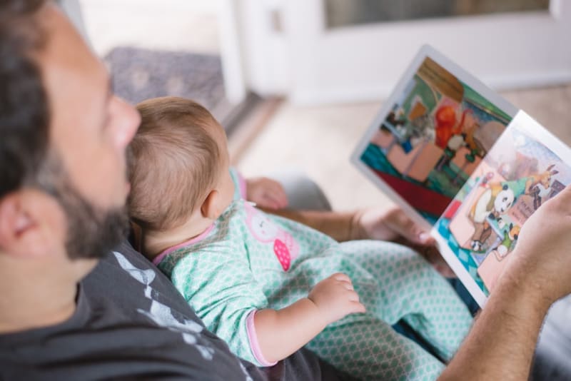 Person with baby on lap reading a children's book to the baby