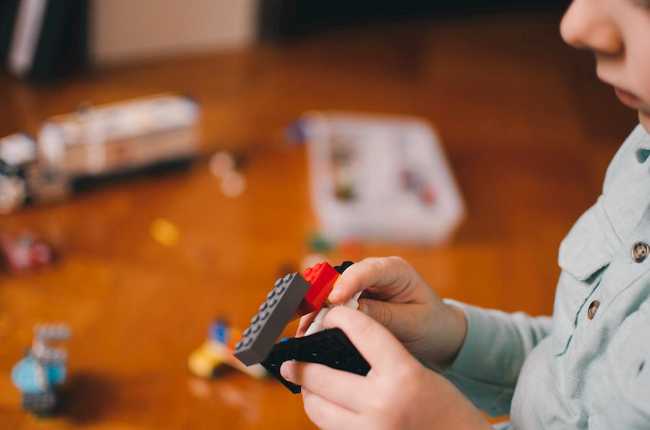 Photo by Kelly Sikkema of a child building a rocket ship out of legos