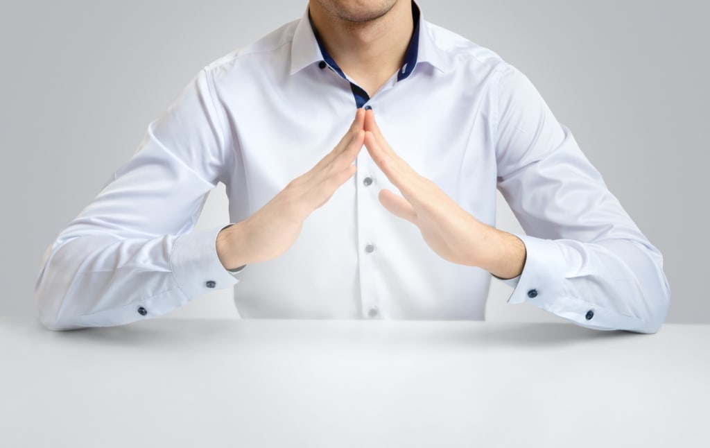 Hire a Website Designer 7 Iman on a light background in a white shirt, folded his hands in the form of a roof
