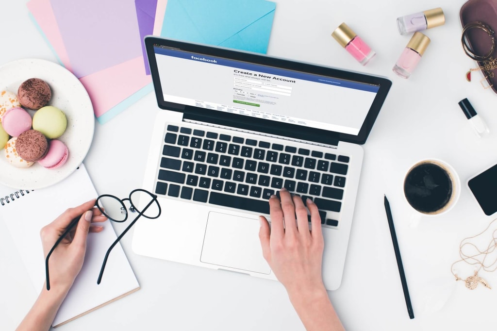 Web Design Company in Andheri 8 top view of woman using laptop and holding eyeglasses in hand with facebook website