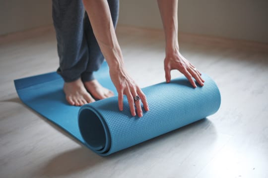 Person standing on a yoga mat while they roll it out