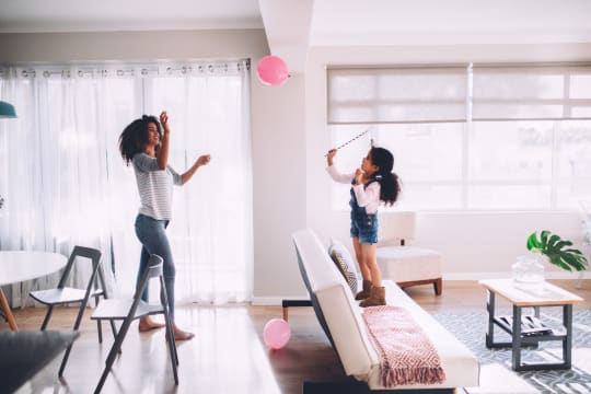 Mom and child playing with balloons in the living room