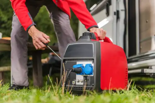 A photo of a man trying to start a gas-powered generator with a pull crank