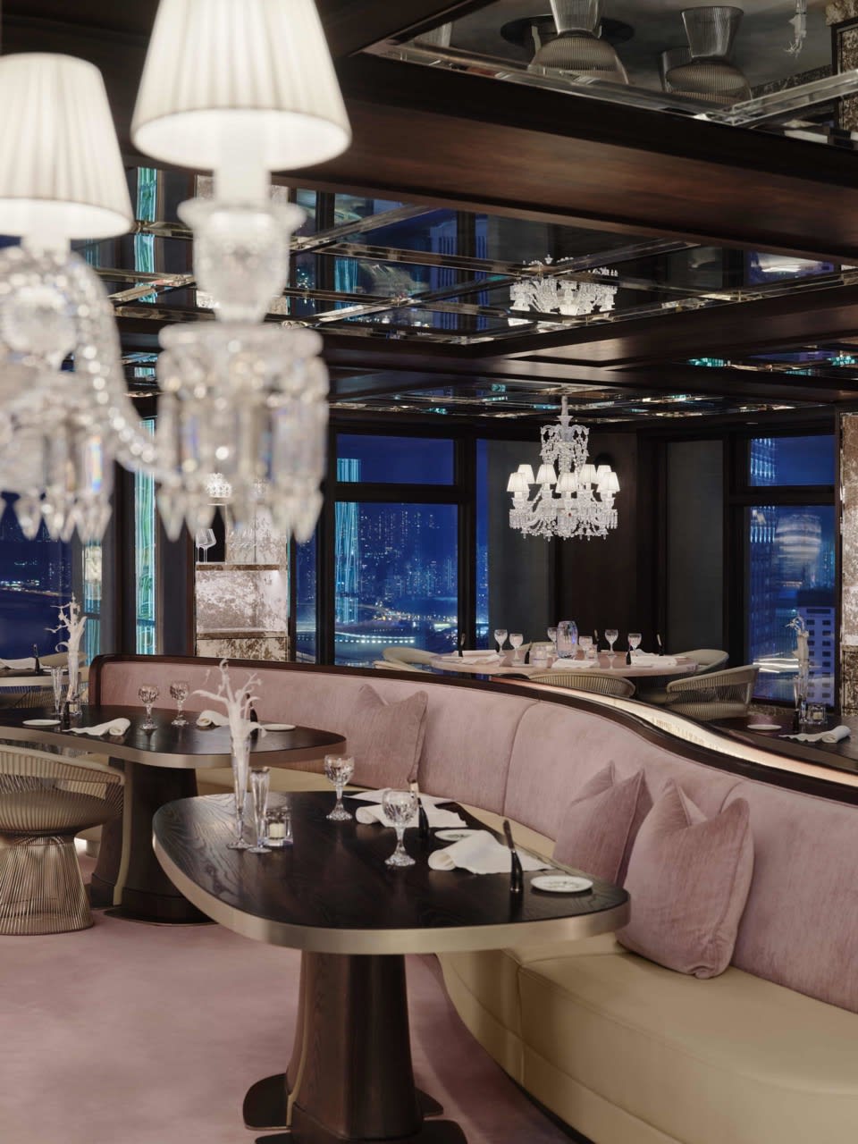 Cristal Room by Anne-Sophie Pic à Hong Kong aménagée par Gilles&Boissier, avec lustres en cristal Baccarat, banquettes rose poudré et vue sur la skyline.