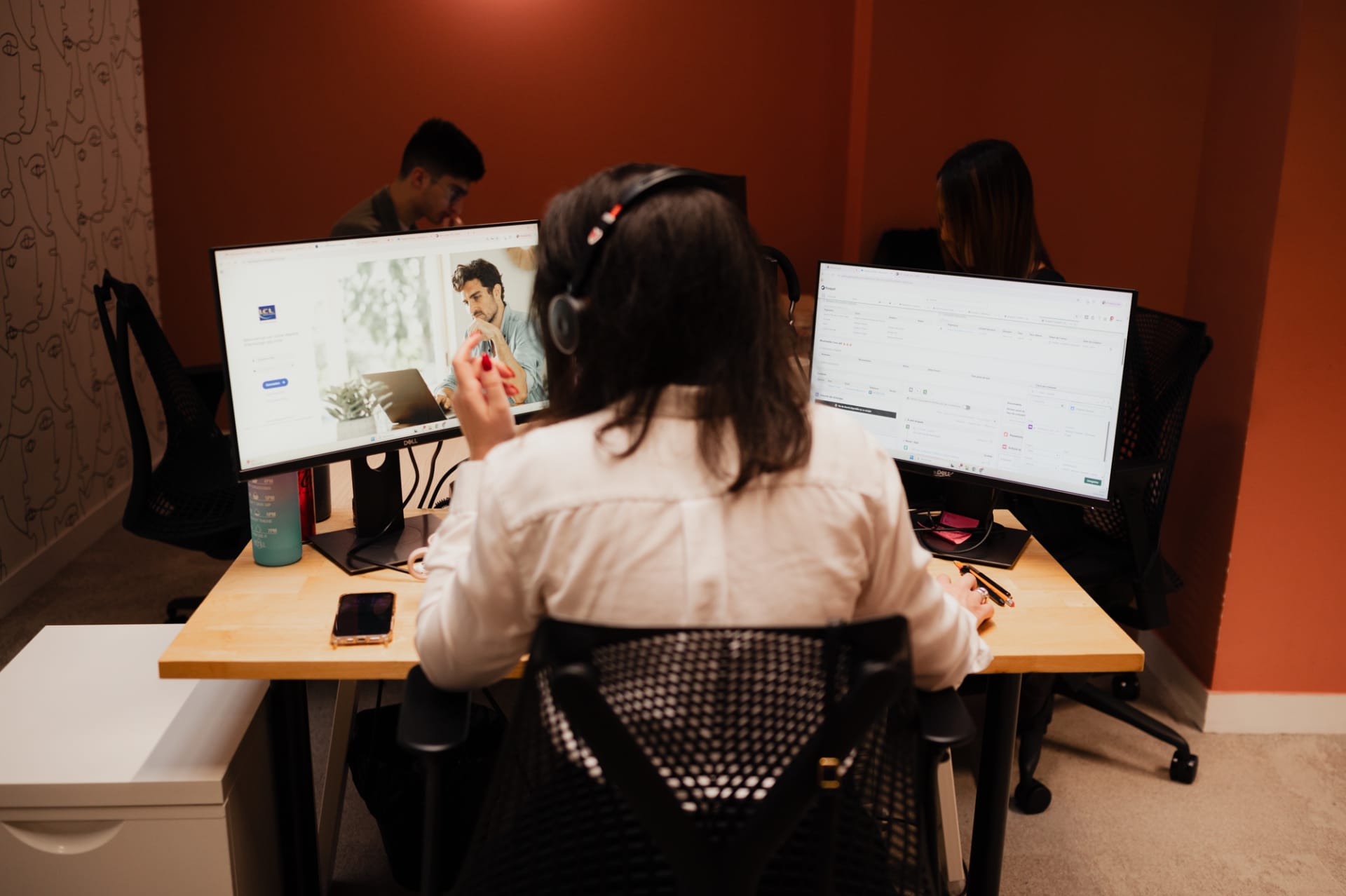 Une courtière de dos, devant ses écrans d'ordinateurs