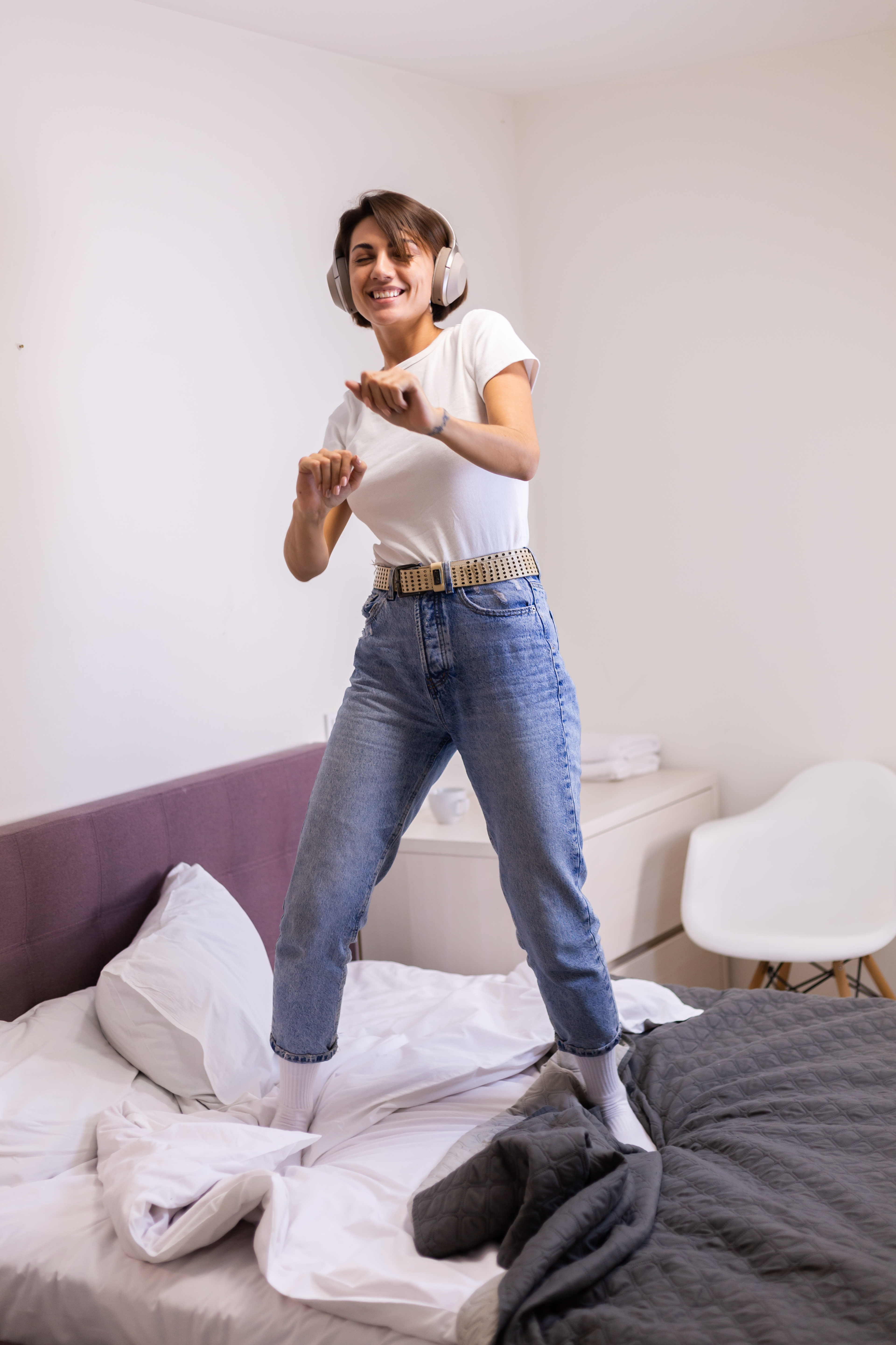 Une femme qui danse sur son lit, casque sur les oreilles