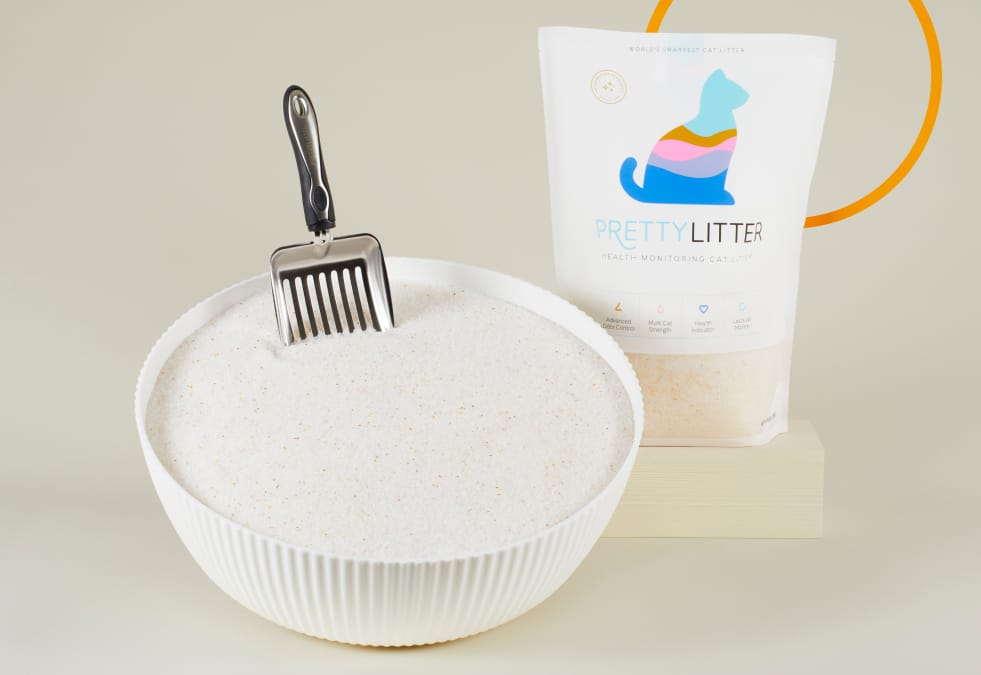 A bowl of PrettyLitter with a scoop and a bag of PrettyLitter