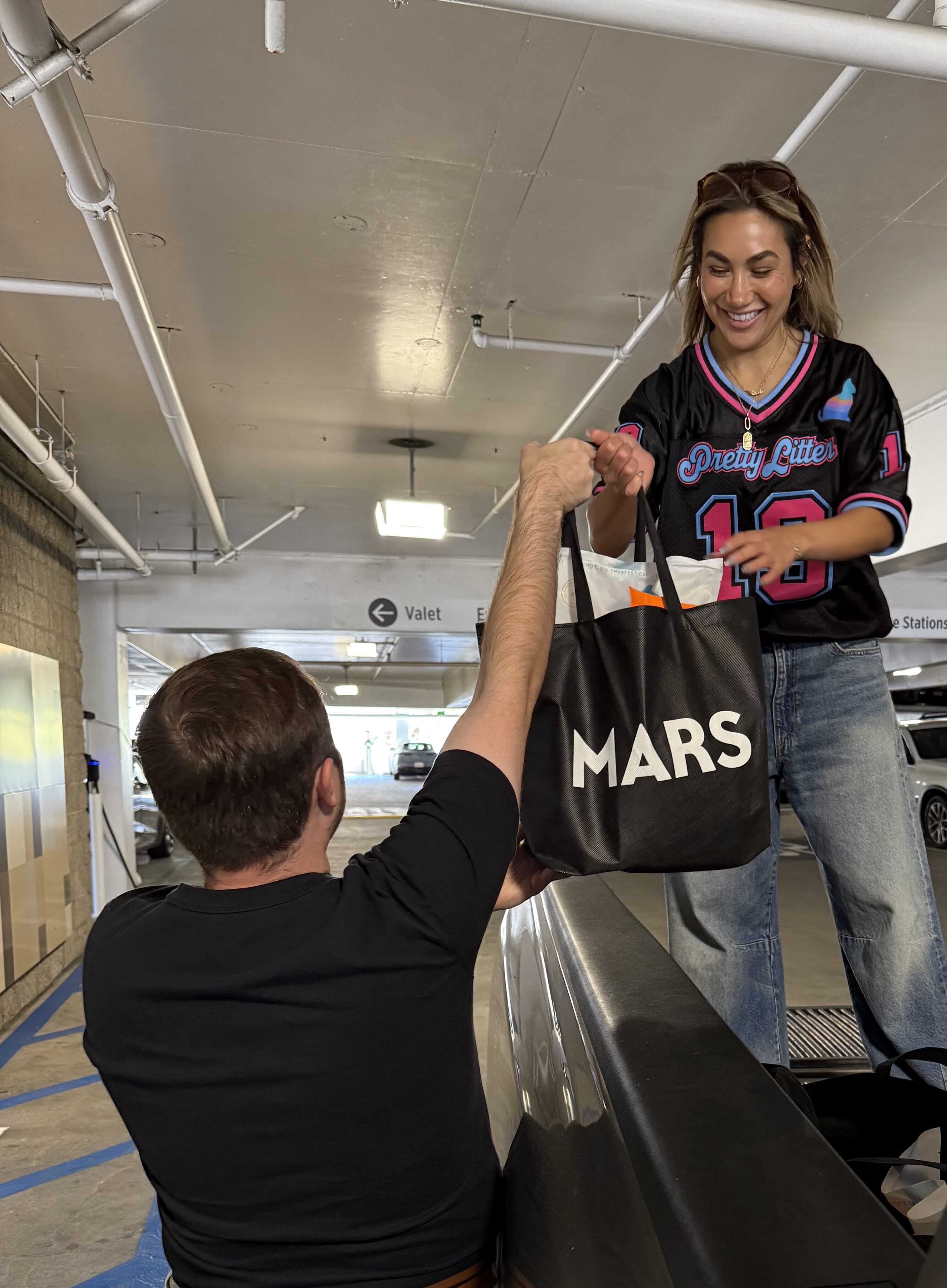 Four people in masks holding PrettyLitter bags in front of a green van