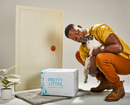 Man holding cat with PrettyLitter box being delivered