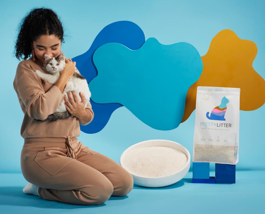 Woman holding cat next to litter box and PrettyLitter bag