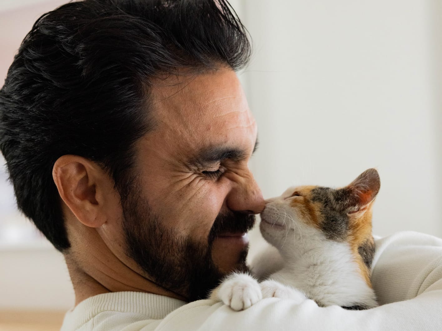 Man with cat touching noses each other