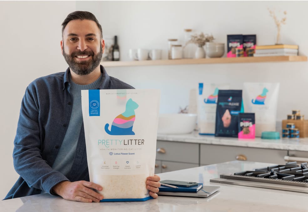 Daniel is standing in front of a counter with various PrettyLitter products