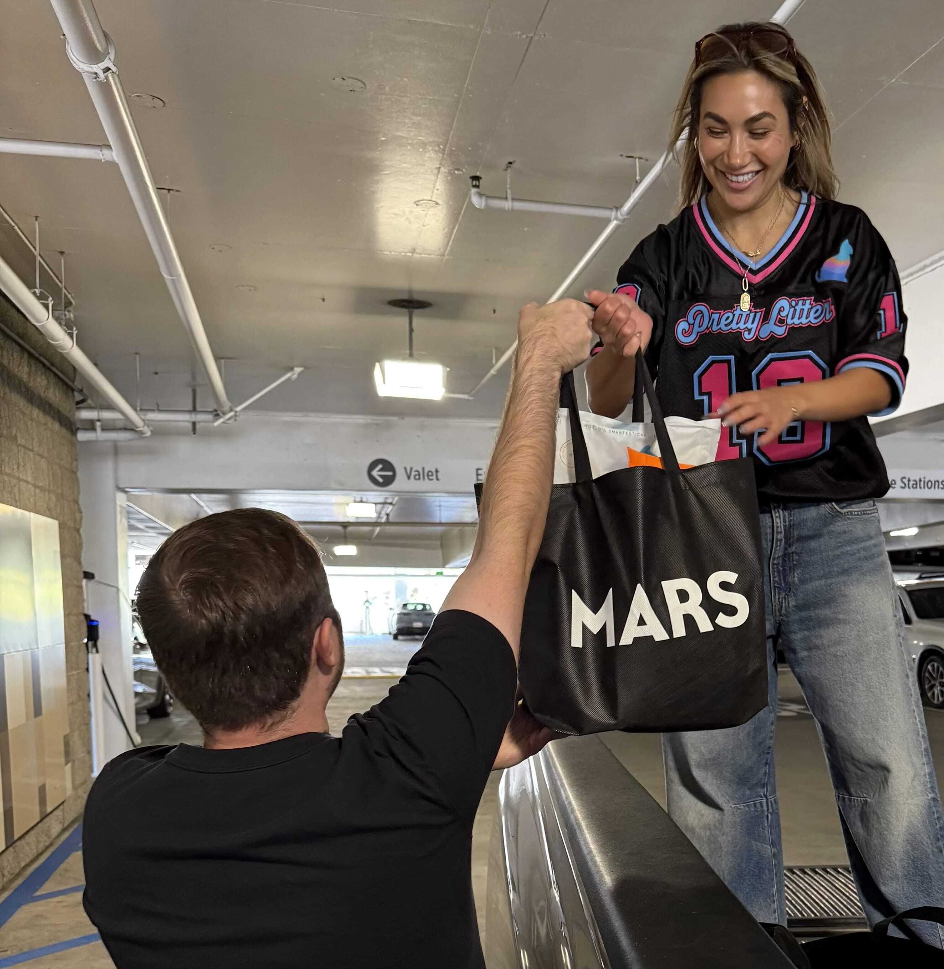 Four people in masks holding PrettyLitter bags in front of a green van