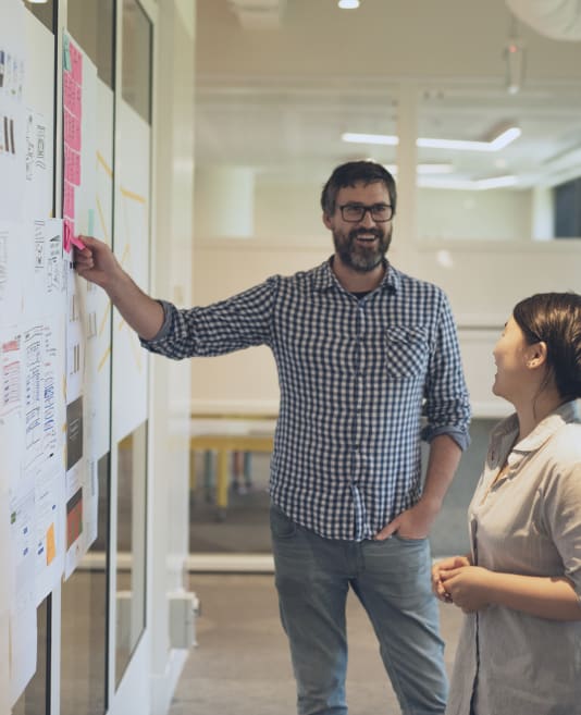 Two people pointing to the wall with prototypes