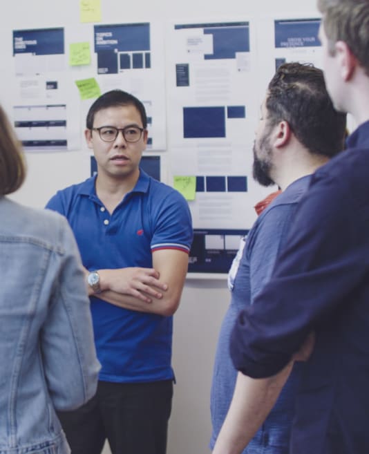 Group of people discussing in front of a board of wireframes