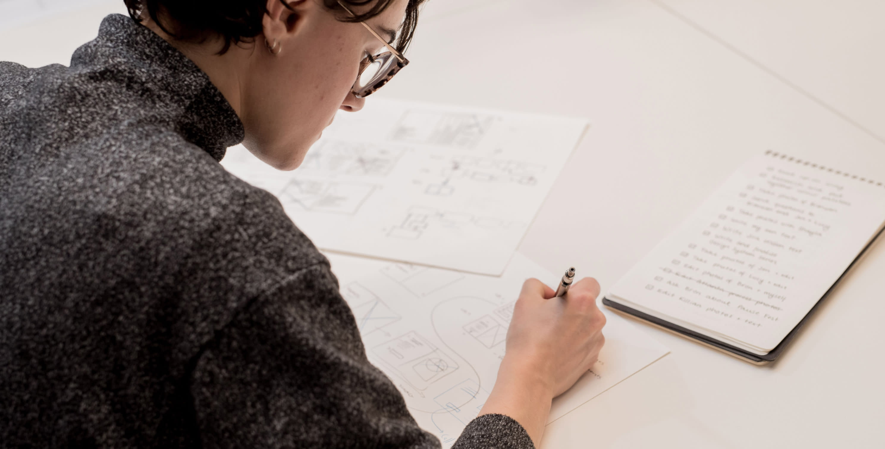 Person sketching user journeys with a pen on paper