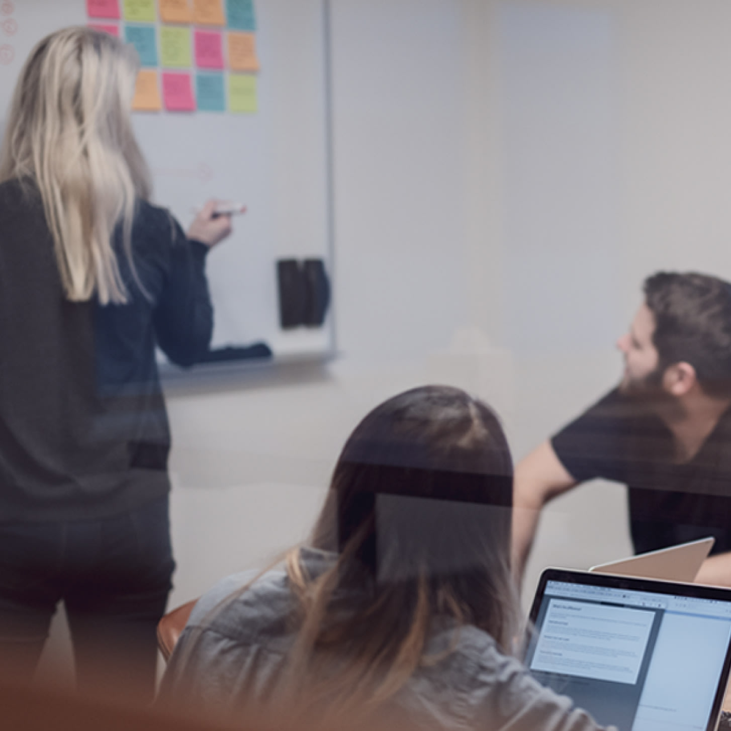 Researchers sitting at a table, looking at a whiteboard
