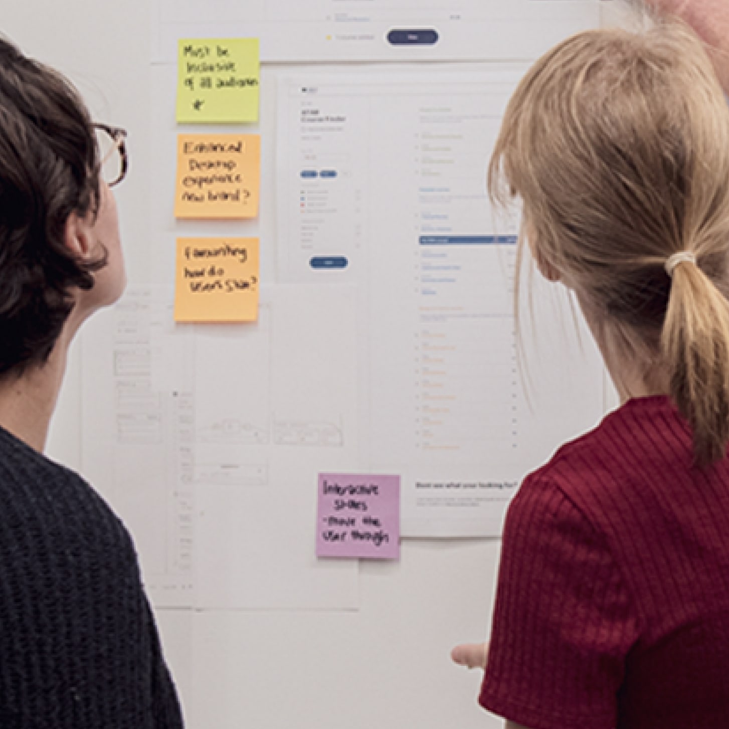 Researchers looking at a whiteboard covered in sticky notes
