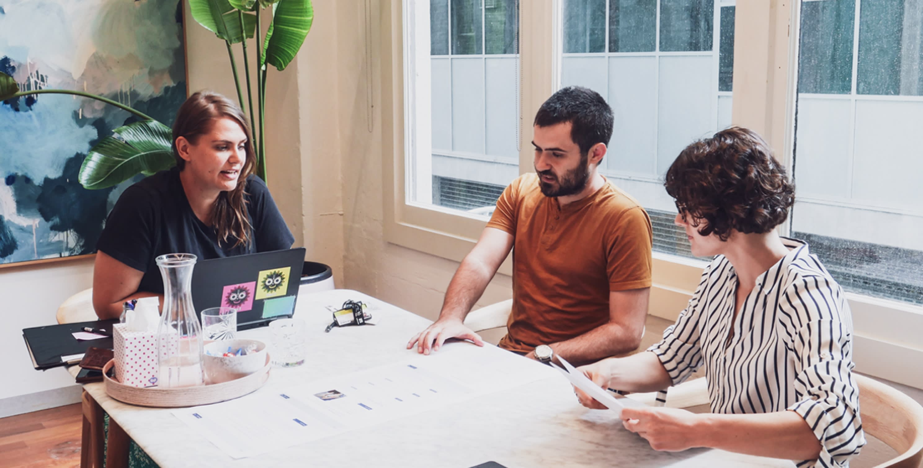 Photograph of three people sitting at a table sharing ideas