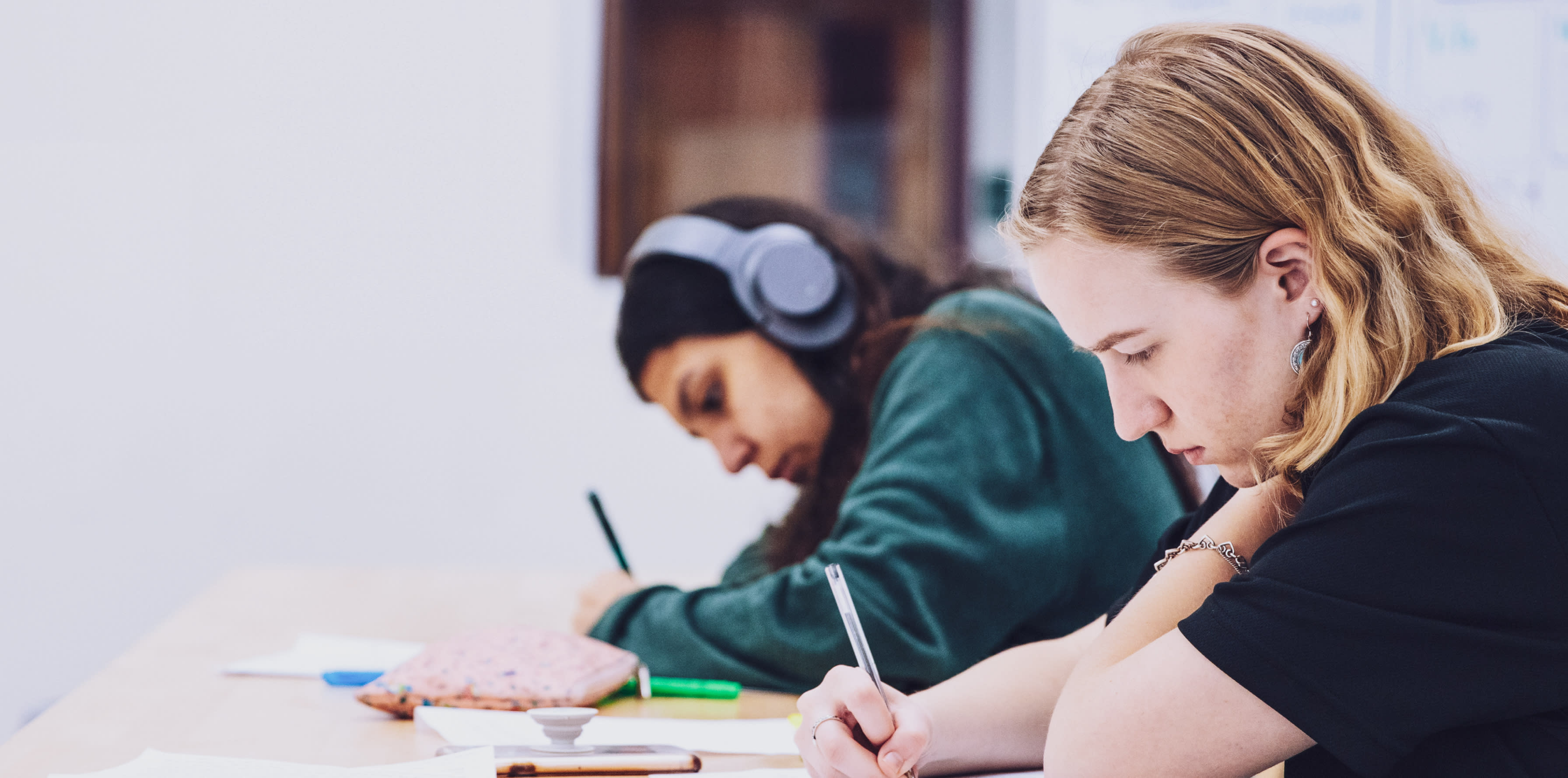 Two people sitting at a desk writing