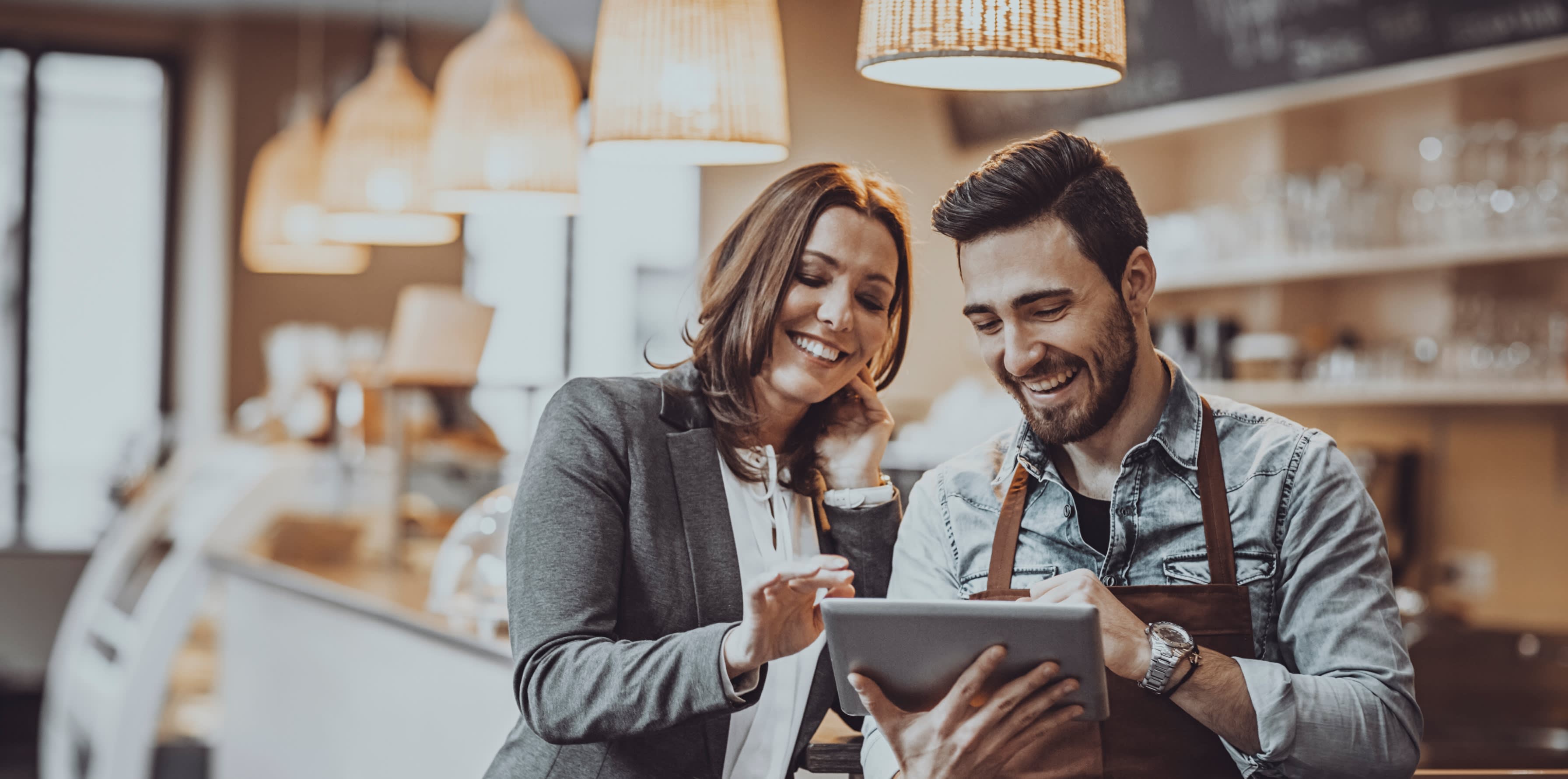Two people in a cafe looking at an iPad screen