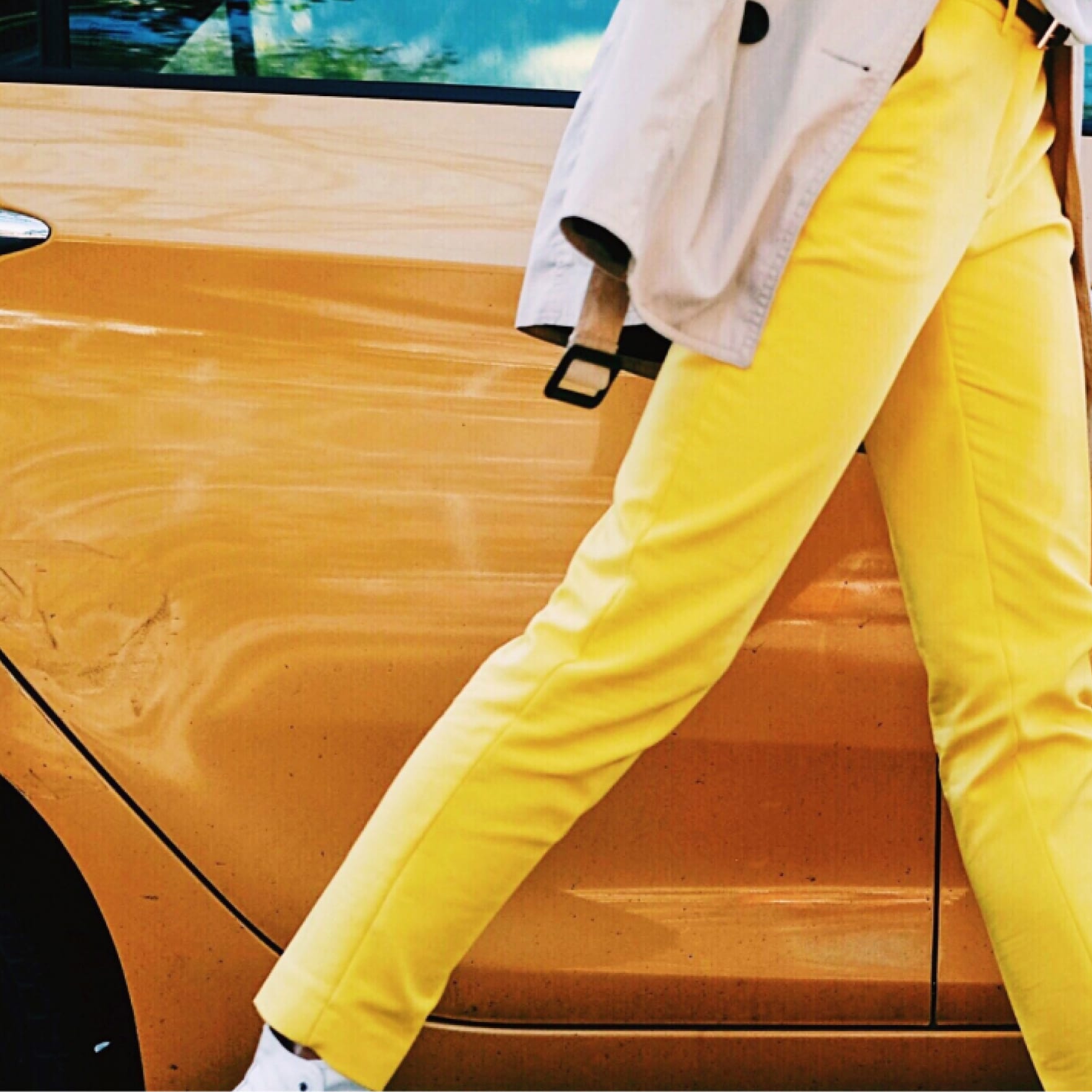 Shot of person's yellow pants against gold-orange car door