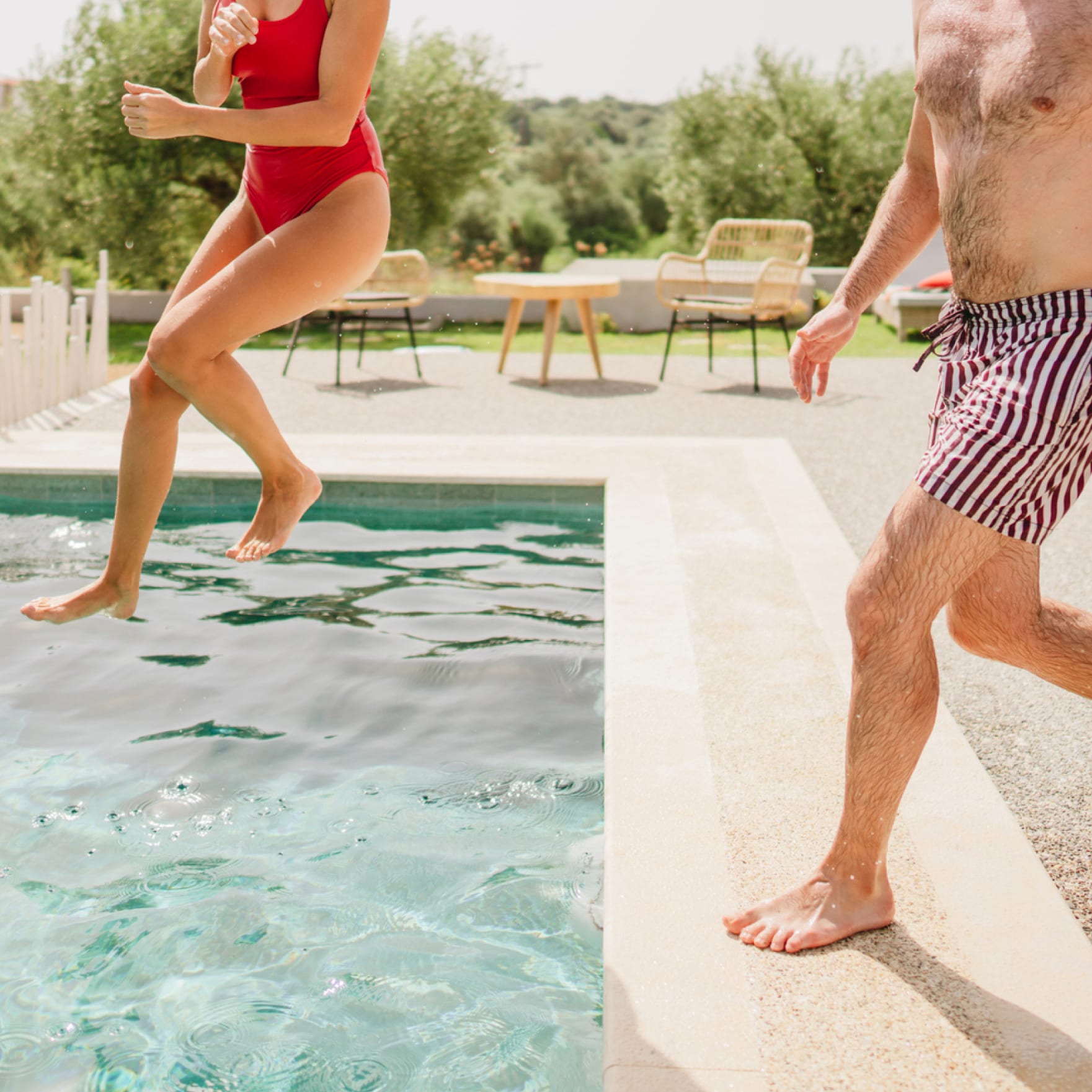 Two people jumping into a pool