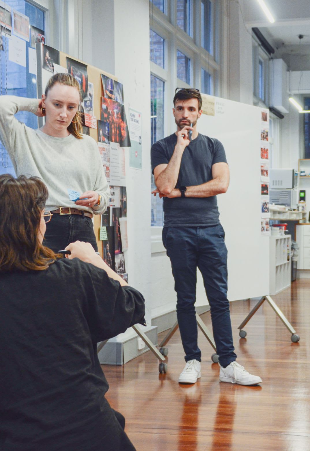 Small group workshopping in a large airy room, with whiteboard behind them