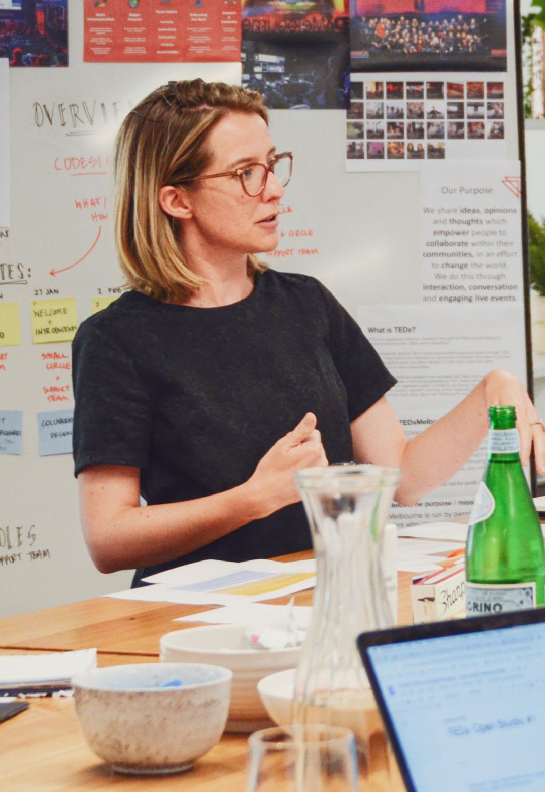 Woman standing at a tall table in front of a whiteboard covering in design concepts