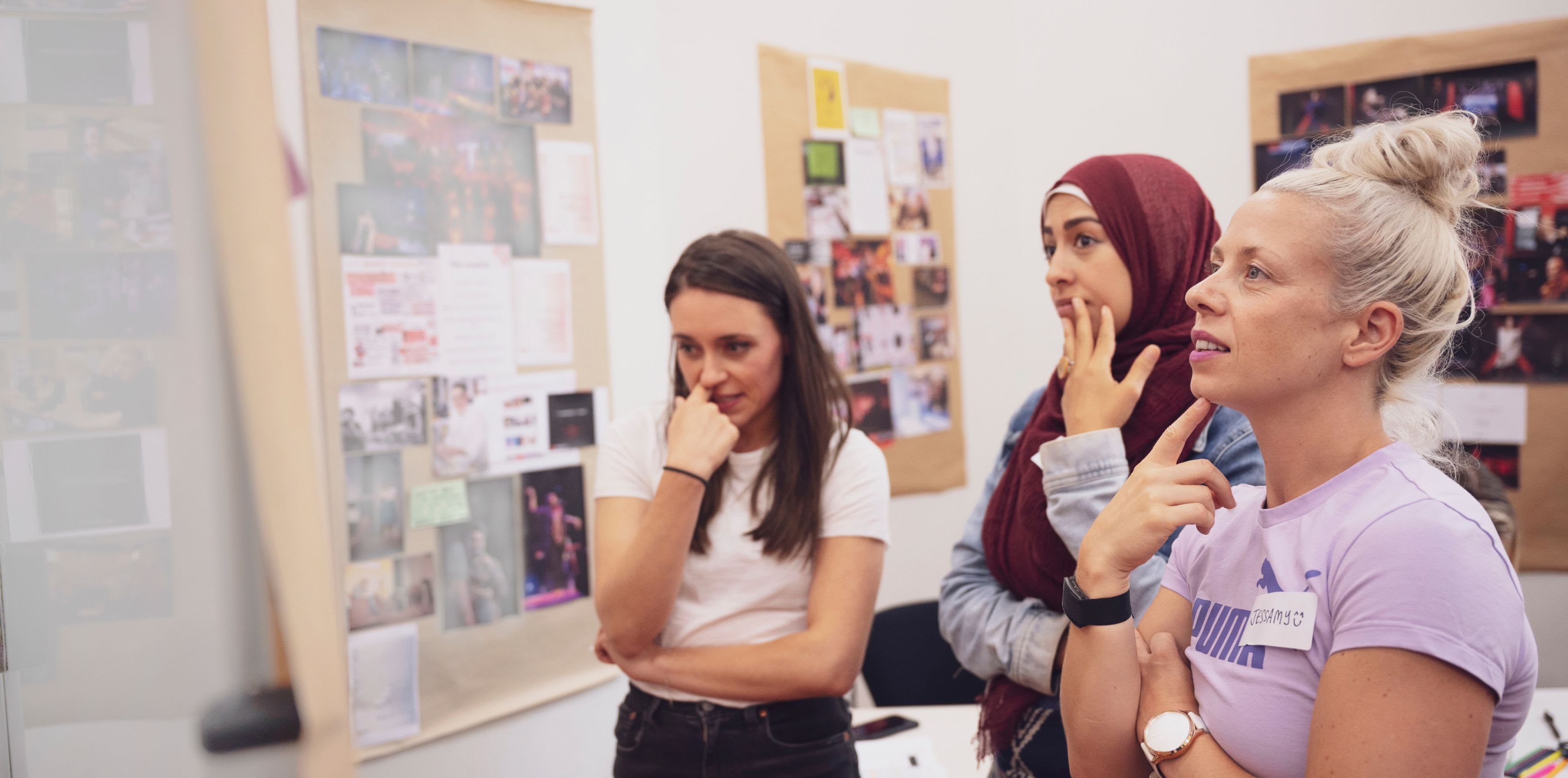 Group of women looking at a presentation, the room is filled with design concepts