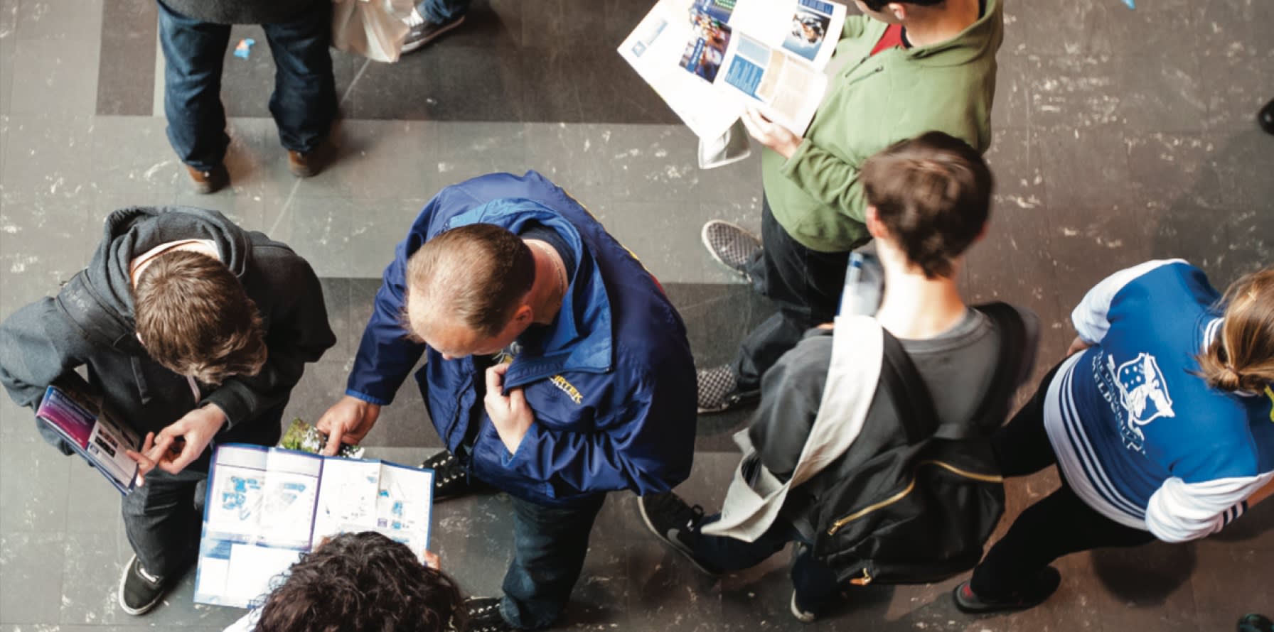 Top down shot of a group of people looking at University of Melbourne brochures and campus maps