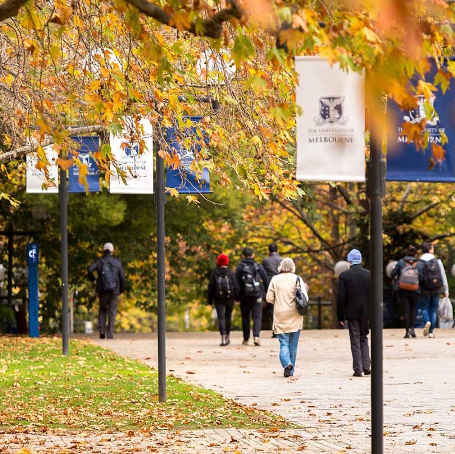 People on a walking path near a park with University of Melbourne signs