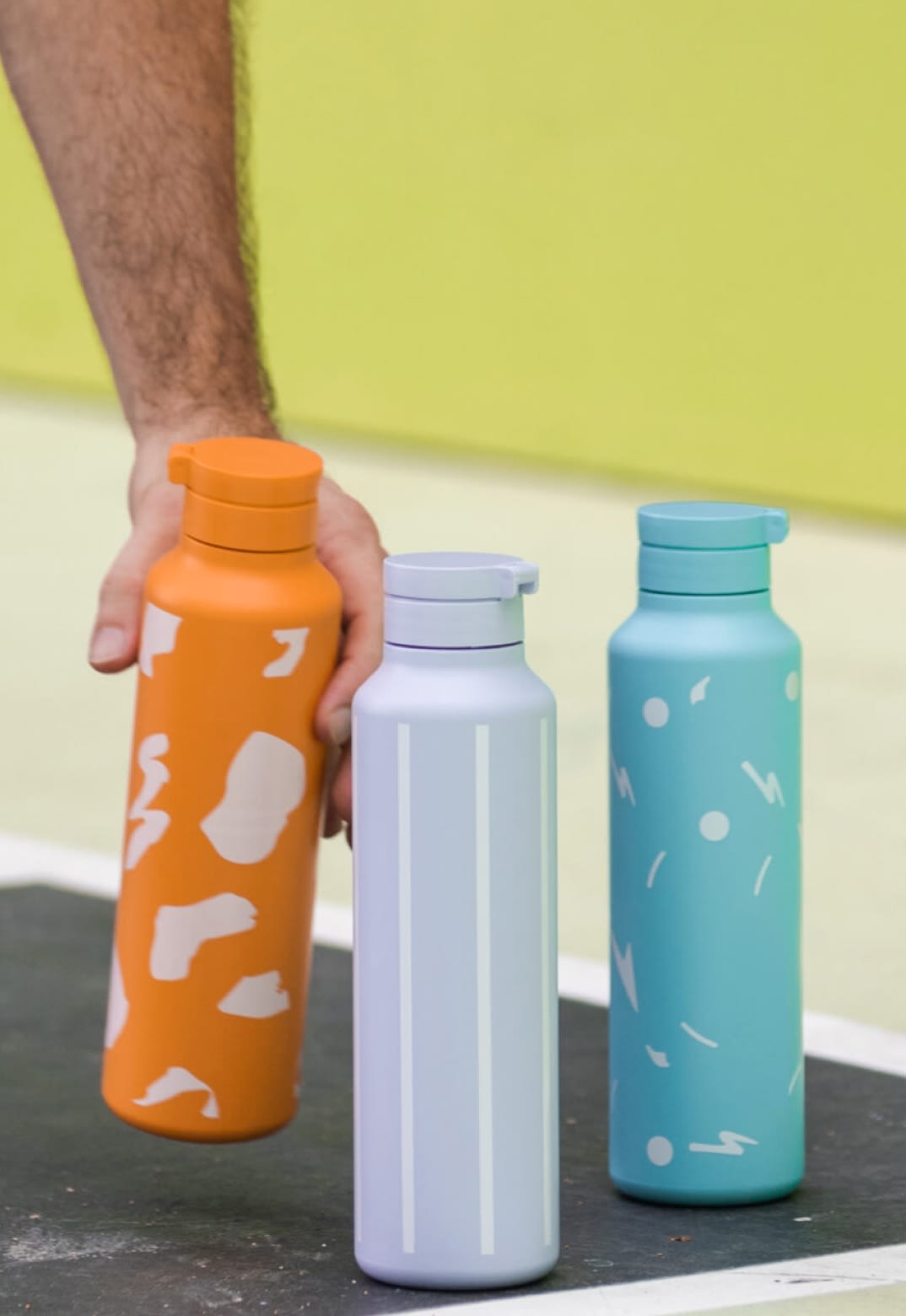 A person holding a water bottle on a basketball court