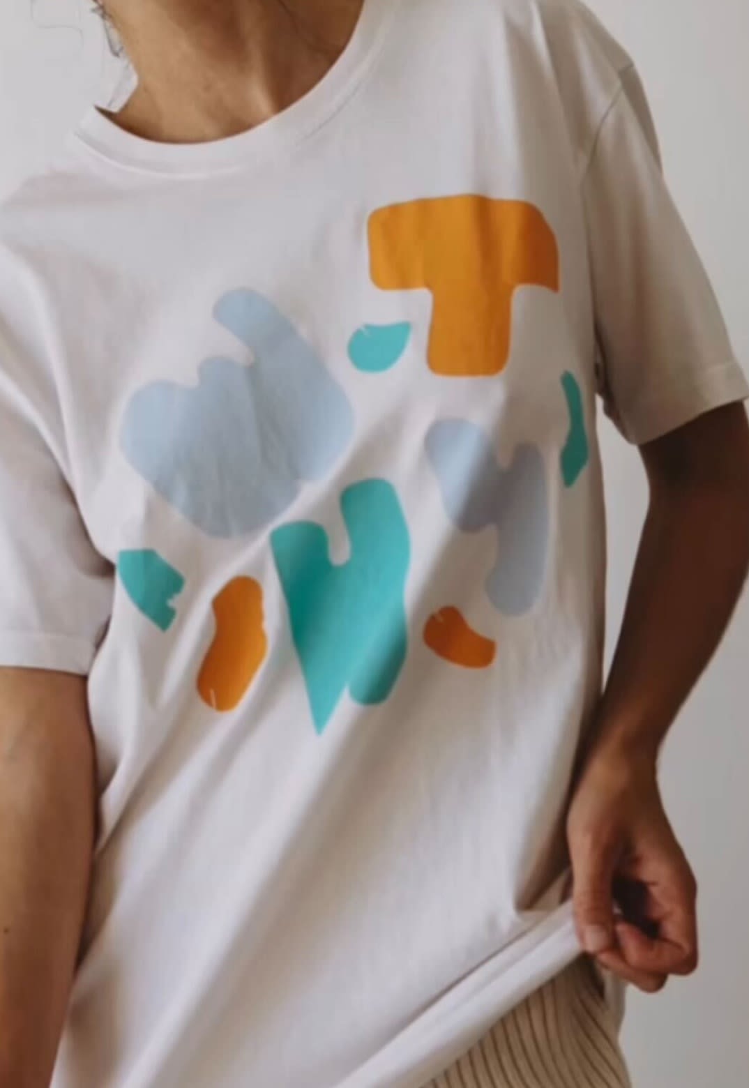 A woman wearing a white t-shirt with colourful letters 