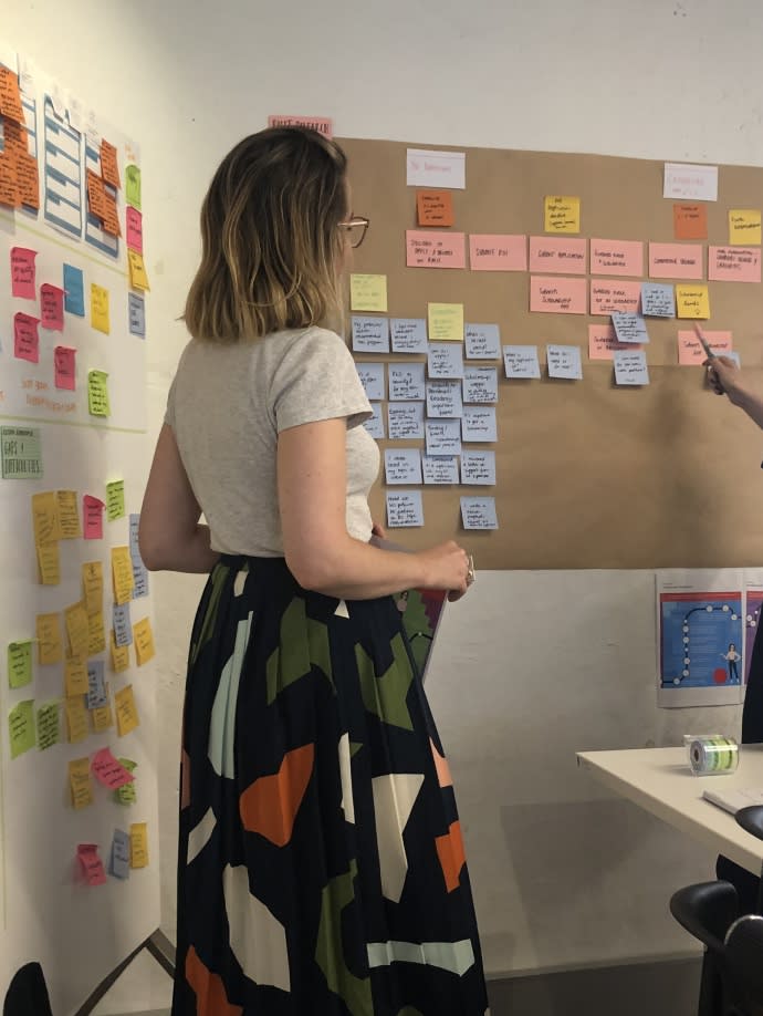 Young woman working on a board with post-it notes of varying colours.