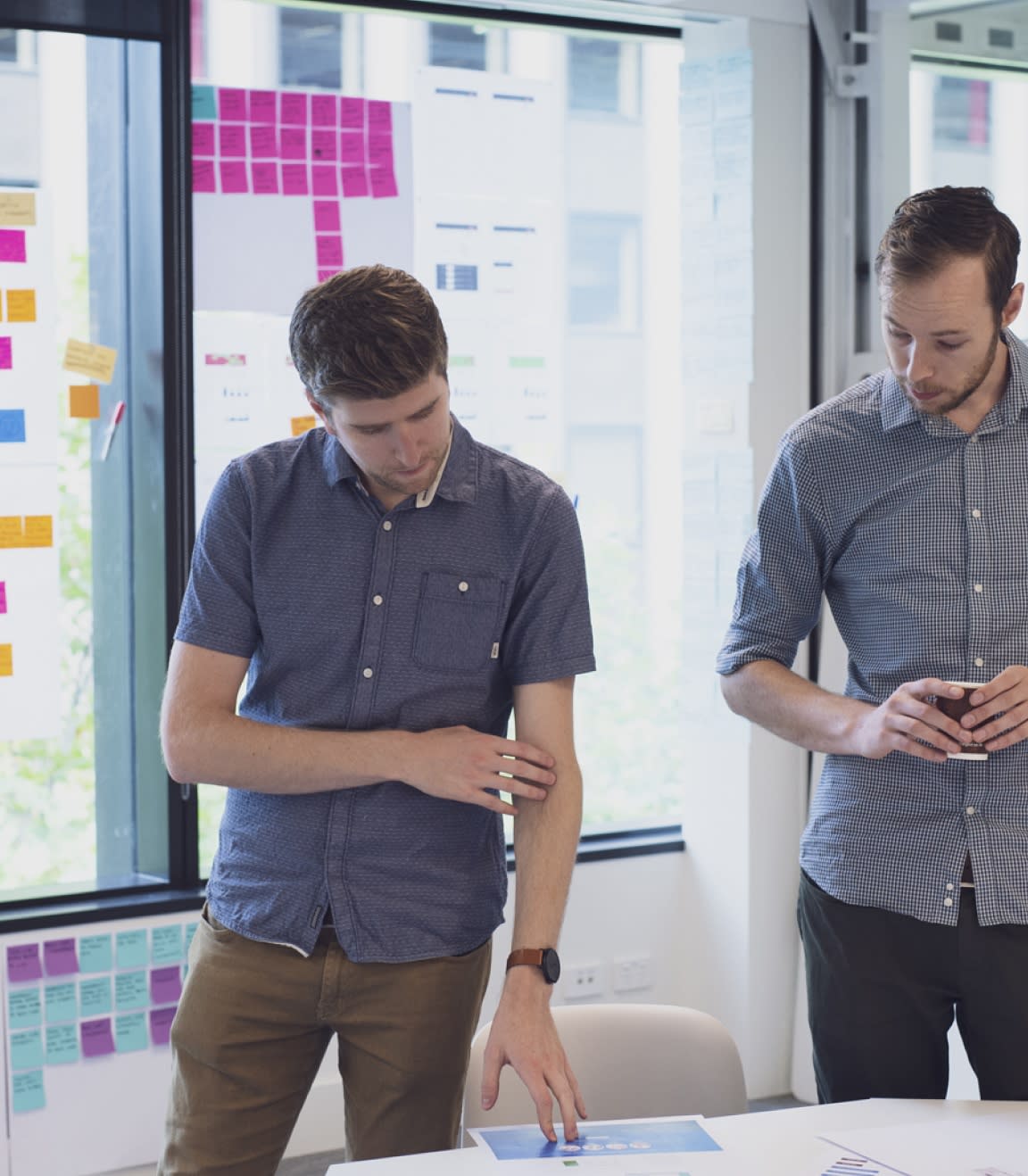 Two people standing discussing wireframes on a table