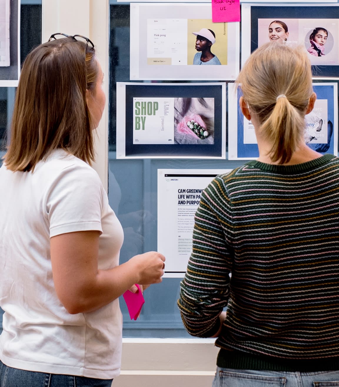 Two people standing near a series of images stuck on a window
