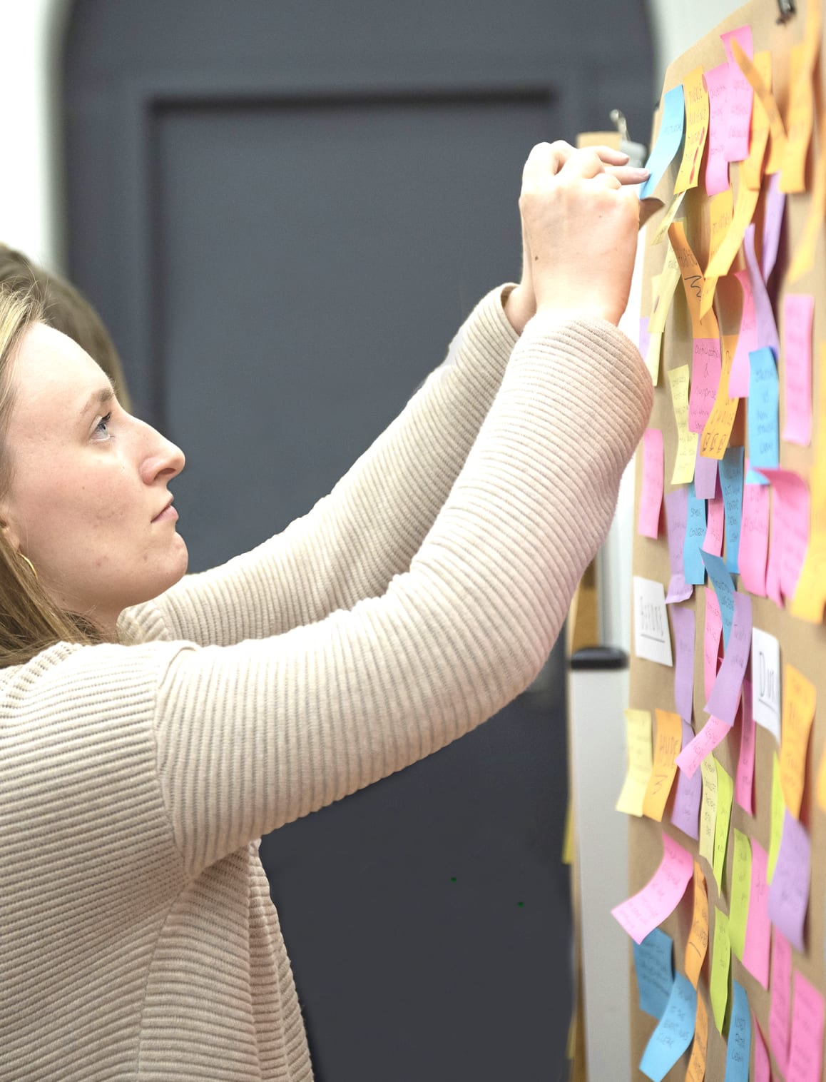 Woman organising a wall of post-it notes