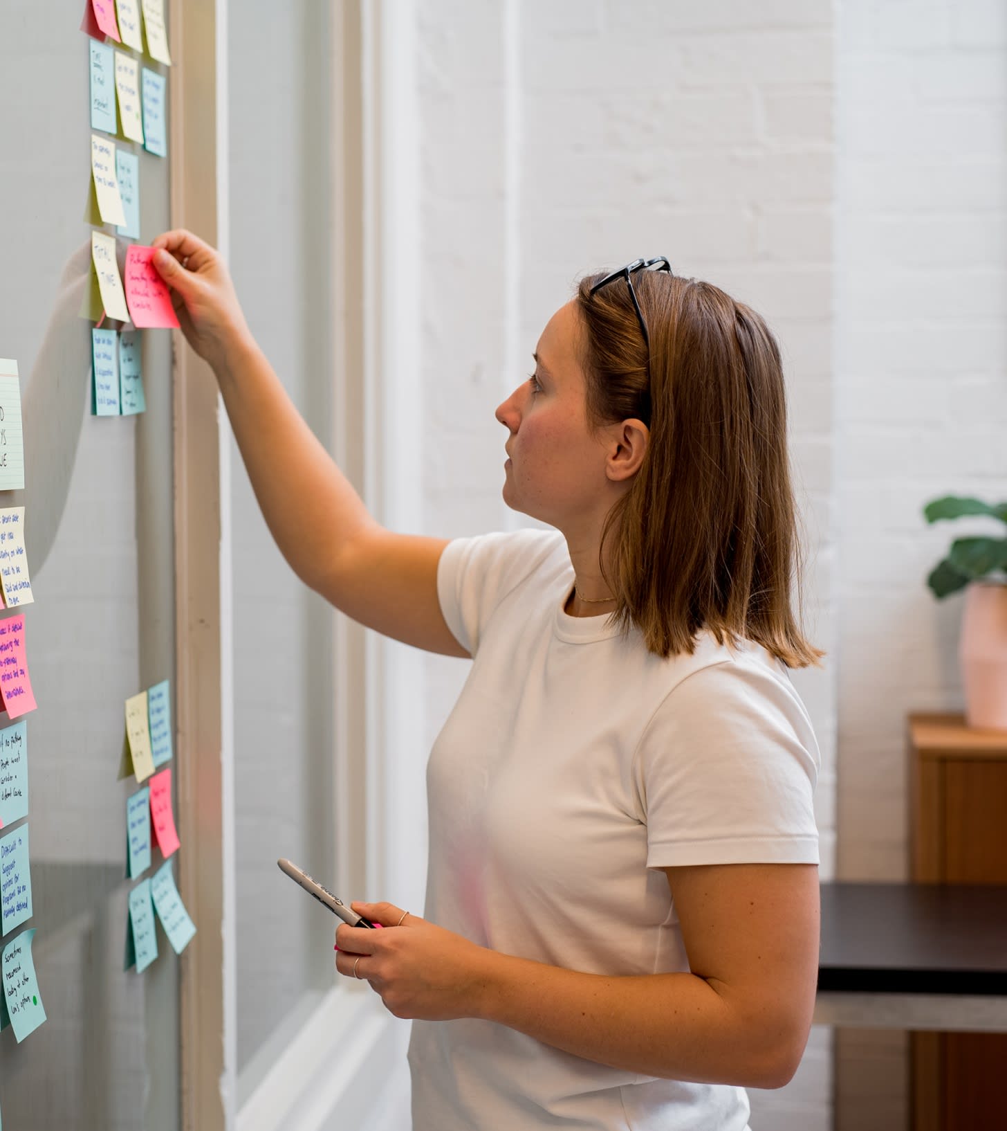 Person picking up a sticky note on a board of sticky notes