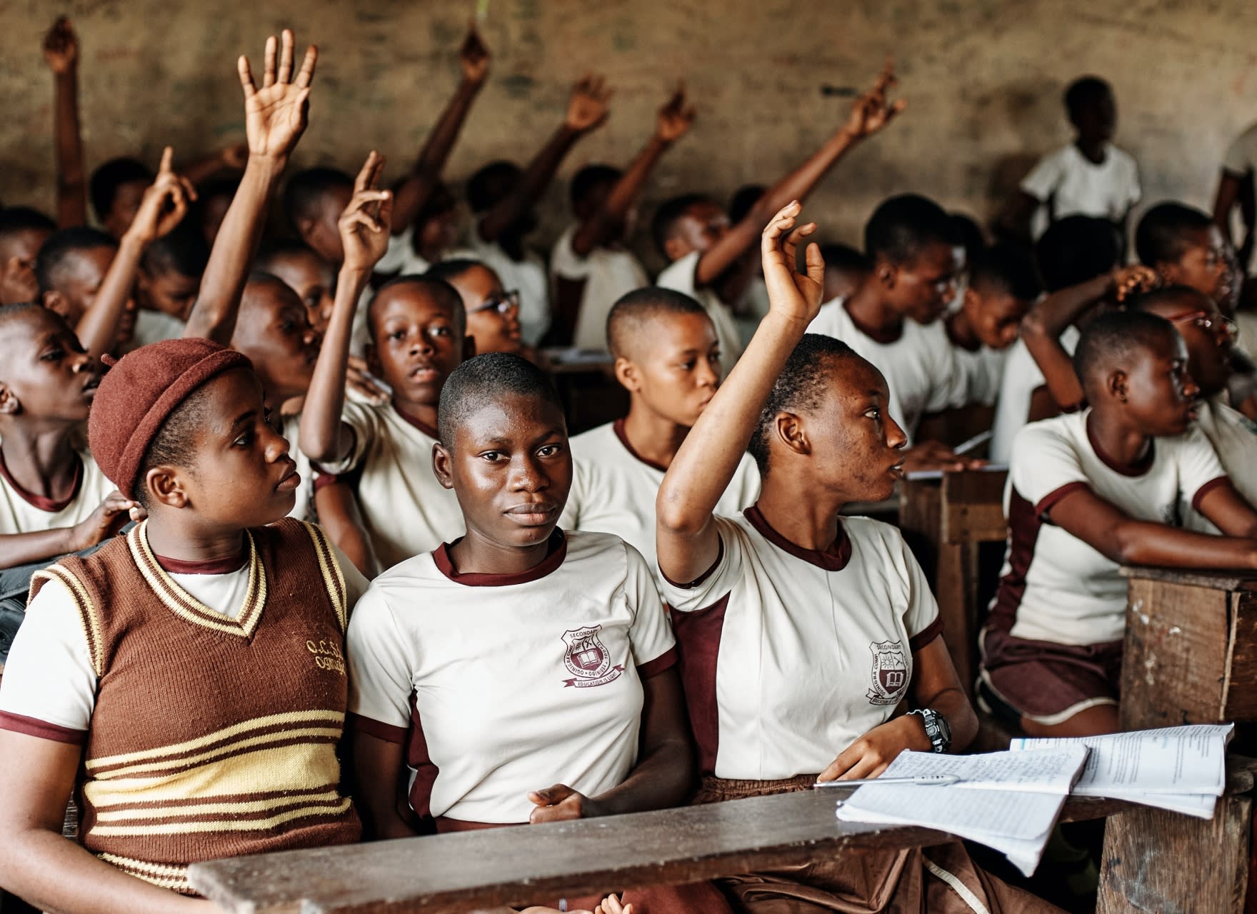 Children putting their hands up in a classroom 