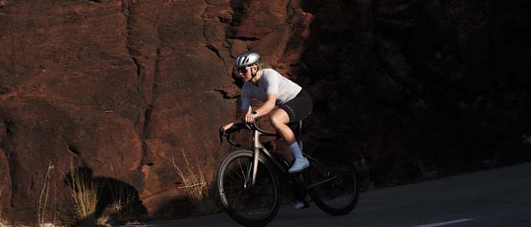 Road cyclist riding on the road in front of rocky terrain.