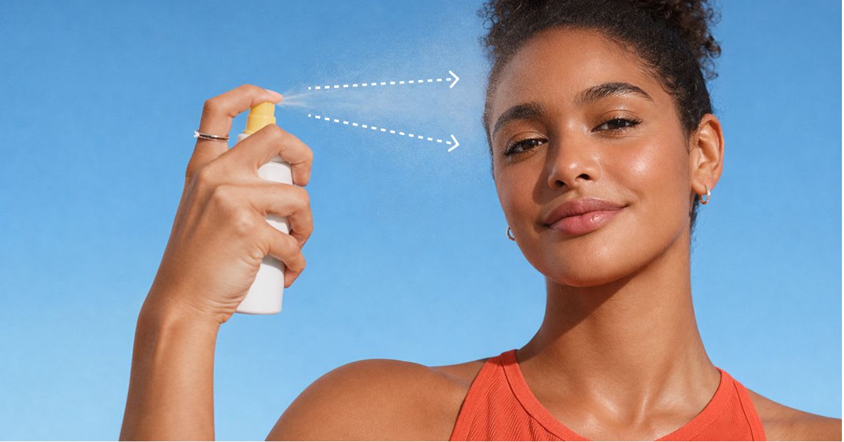 Woman with glowing skin spraying facial mist onto her face, shown with fine mist droplets and directional arrows, against a bright blue background.