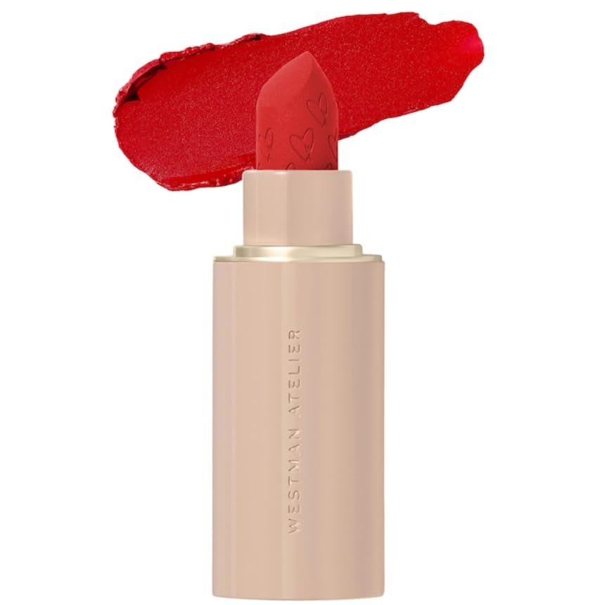 Westman Atelier lipstick in a vibrant red shade, shown in a sleek nude-toned tube with an embossed bullet, with a matching red lipstick swatch behind it on a clean white background.