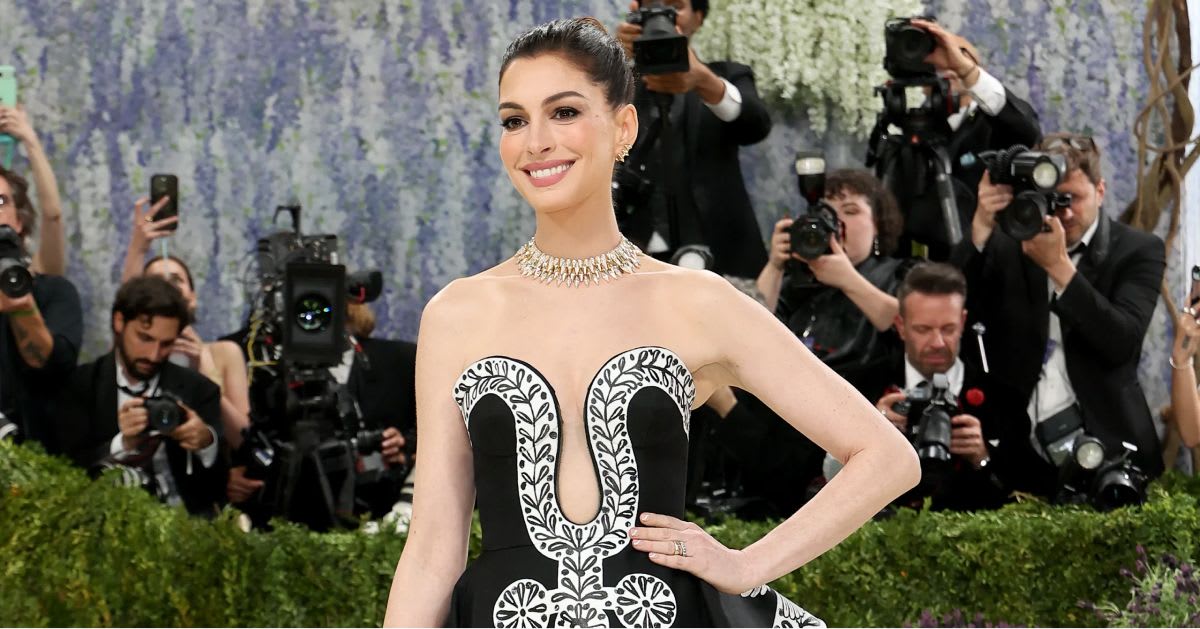 Anne Hathaway — Anne Hathaway on the Met Gala red carpet in a black and white strapless gown with floral embroidery detailing