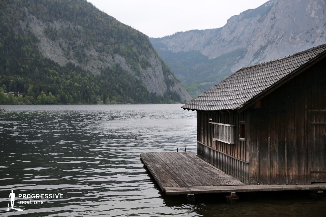 A weathered wooden boathouse sits quietly on a calm lake, framed by steep forested hills and rugged cliffs in the distance. The structure’s dark wood and simple lines blend seamlessly with the natural tones of the surrounding landscape, while the still water enhances the mood of solitude. This evocative location is perfect for character-driven dramas, romantic interludes, mystery scenes, or stories centered on isolation, introspection, or escape from the outside world.