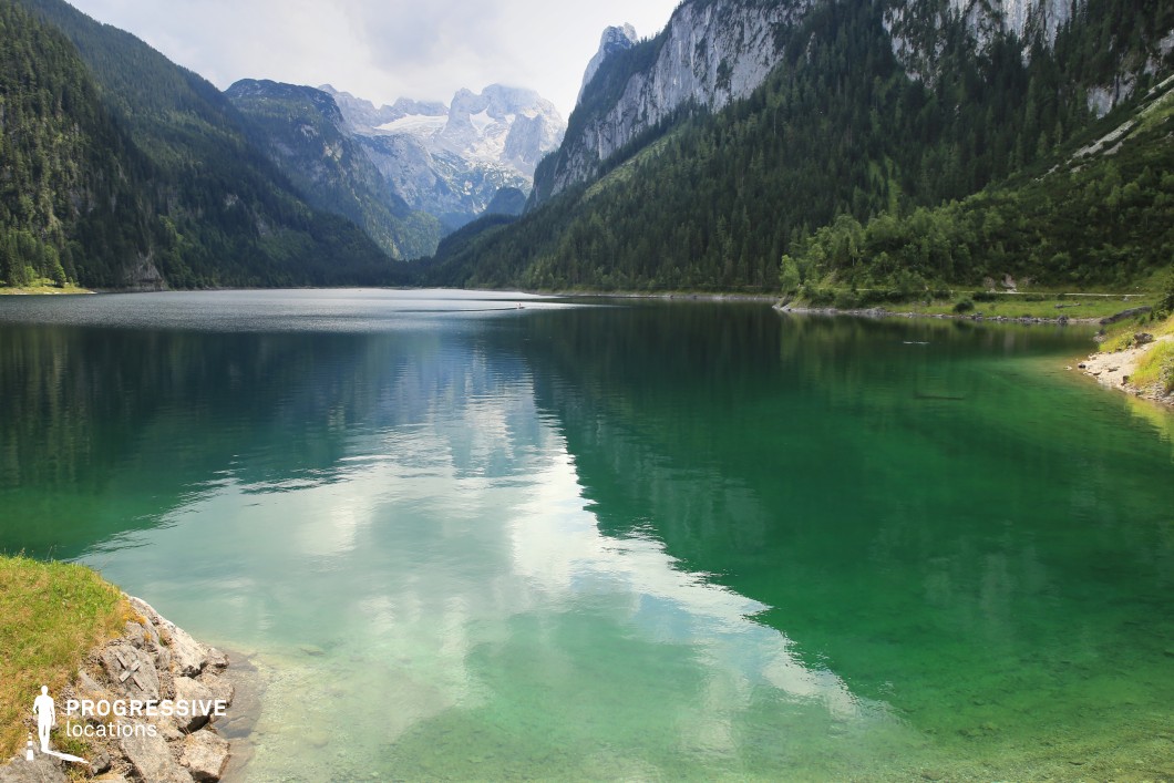 This glacial lake is surrounded by towering forested cliffs and dramatic snow-capped peaks, with crystal-clear emerald water reflecting the surrounding mountains and sky. The steep terrain and rich color palette create a visually captivating and immersive setting that feels both majestic and untouched. Perfect for fantasy, epic adventures, or emotional turning points in character-driven films, this location is ideal for scenes involving solitude, discovery, escape, or spiritual encounters in a sublime natural world.
